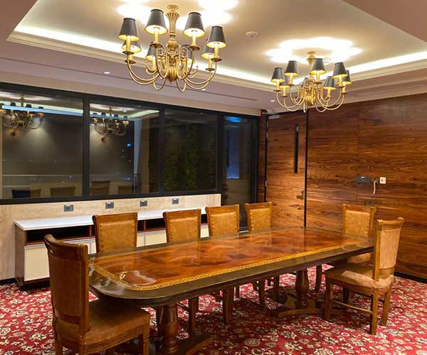 A spacious conference room featuring a long table surrounded by several chairs, ready for a meeting.