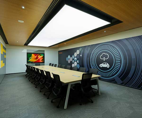 Project Visteon: A conference room featuring a large screen and a wooden wall designed for meetings and presentations.